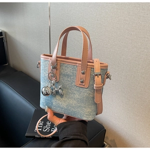 Detailed side view of mini denim tote bag with silver studs and pink leather trim