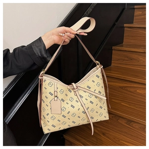 Detail showing bear pattern texture and decorative leather bow on the beige shoulder bag