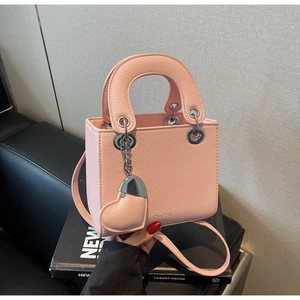 Detail of pink lychee leather handbag with heart pendant and round handles
