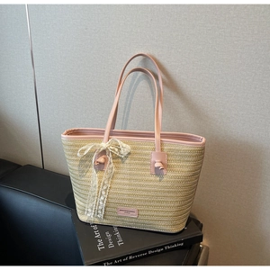 Détail d'un sac cabas en paille tissée avec bordure en similicuir rose et nœud en dentelle