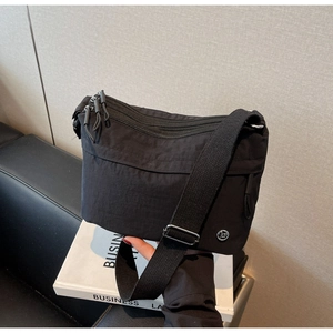 Detail of black nylon crossbody bag with multi-zipper layers and adjustable canvas strap