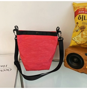 Dettaglio della borsa a tracolla rossa in nylon con fibbia metallica e tessuto stropicciato