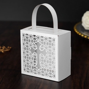 Macro detail of white laser-cut cross favor box with intricate lace hollow patterns