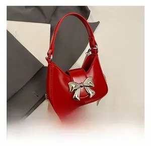 Détails d'un sac demi-lune en cuir rouge brillant avec nœud métallique argenté et chaîne