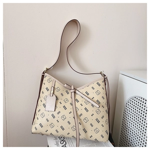 Detailed view of beige monogram tote bag featuring cartoon bear motifs and bow detail