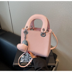 Detail of light pink mini crossbody bag with litchi grain leather and heart pendant