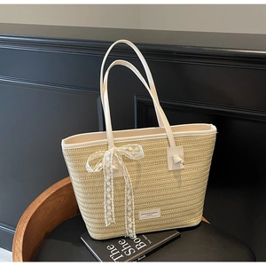 Détail du sac cabas en paille avec nœud en dentelle blanche et anse en cuir
