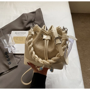Detail of woven straw bucket bag with leather trim, pearl charm and lace accessory