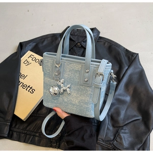 Close-up of light blue mini tote bag with silver rivets and balloon dog charm