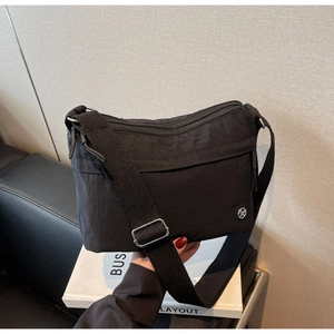Detail of black nylon crossbody bag with multiple zippers and adjustable woven strap