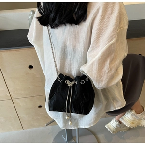 Détail d'un sac seau en satin noir avec papillon argenté et cordons en perles