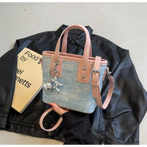 Detail of blue denim mini tote bag with pink leather trim and silver balloon dog charm