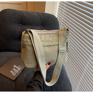 Close-up of olive green nylon crossbody bag with multi-layer zippers and wide strap