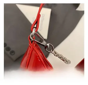 Détail du sac rouge à nœud avec crochets en métal argenté et bandoulière chaîne