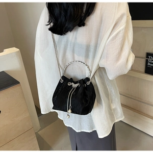 Détail du sac seau en satin noir avec anse anneau argenté, papillon et pompon en perle
