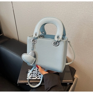 Macro shot of light blue lychee pattern leather handbag with silver heart charm detail
