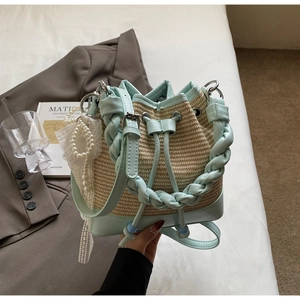 Detail of woven straw bucket bag with mint green leather trim and pearl charm accessory