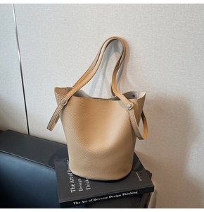 Detailed macro shot of premium lychee grain leather on a khaki bucket handbag
