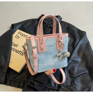 Detail of blue denim mini bucket bag with pink leather trim and a silver balloon dog charm