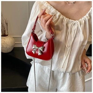 Vue détaillée du sac bandoulière rouge brillant avec nœud métallique argenté et chaîne