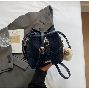 Detail of snake-embossed navy bucket bag featuring gold hardware and a plush charm