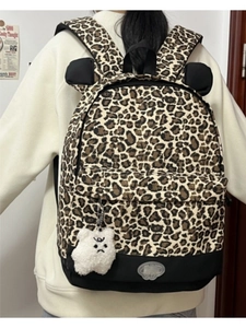 Detail view of leopard print backpack featuring cute decorative ears and plush bear charm