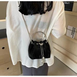 Détail du sac seau en velours noir avec poignée anneau argentée et breloque noeud métal