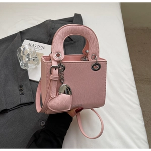 Detail of pink lychee grain leather bag with heart charm and silver hardware on blazer