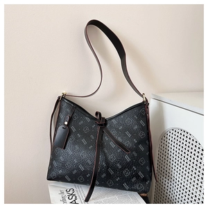 Detail of black tote bag featuring litchi texture, bear patterns and wide shoulder strap