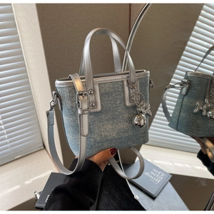 Detail of denim and silver bucket bag with balloon dog charm and rhinestone accents