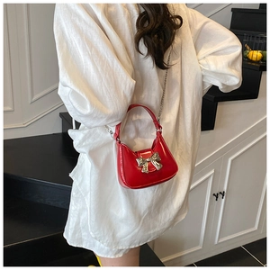 Vue détaillée d'un mini sac rouge à nœud avec chaîne argentée et finition cuir verni