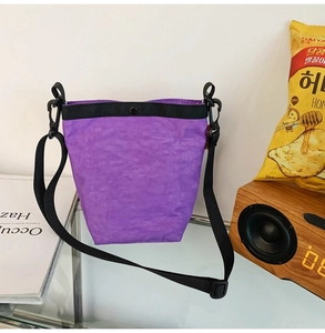 Dettaglio borsa a tracolla plissettata viola con cinturino nero e chiusura magnetica