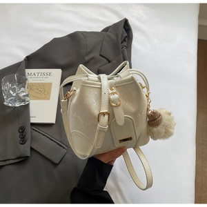 Detail of white snakeskin embossed bucket bag with plush pompom and gold hardware buckle