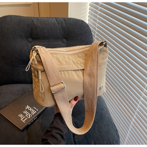 Detail of light khaki nylon tote bag with multi-zipper compartments and adjustable strap