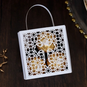 Detail of white laser-cut hollow gift box with elegant floral pattern and chocolate