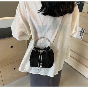 Détail du sac seau noir avec poignées argentées et breloques de nœud en perles