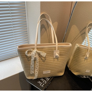 Détail du sac en paille avec garniture en cuir blanc et un nœud en dentelle délicat