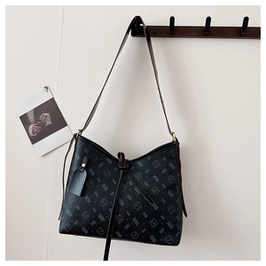 Detail of black printed leather shoulder bag featuring bear motifs on a wall hook