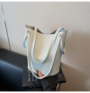 Close-up of light blue lychee pattern leather bucket bag with metal rivet detail