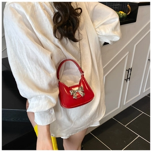 Détail d'un mini sac hobo rouge vif avec fermoir nœud argenté et bandoulière chaîne
