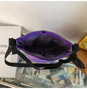 Dettaglio interno della borsa a tracolla in nylon viola con cinturino nero e bottone