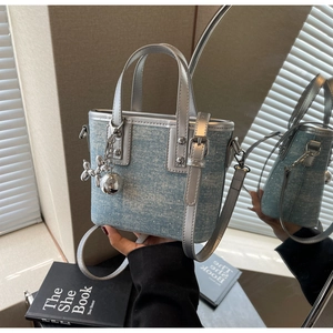 Detail of light blue denim bucket bag with silver trim and metallic balloon dog charm