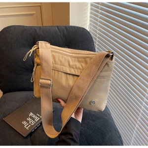 Detail of khaki nylon crossbody bag with wide strap on blue velvet chair with soft light