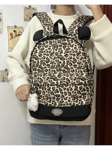 Detailed view of leopard print backpack with cat ears and white plush sheep pendant charm