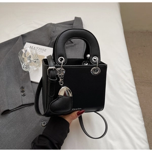 Detail of black litchi grain leather handbag with heart pendant and silver hardware