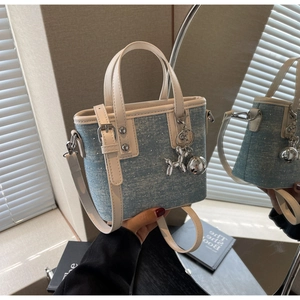 Detail of blue denim mini bucket bag with silver studs and cute dog charm pendant