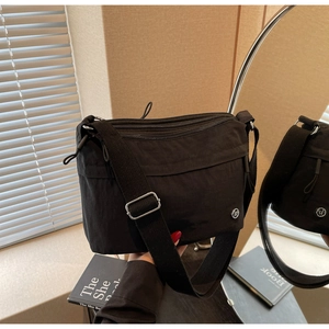 Detail of black nylon crossbody bag with multi-layer zipper pockets and wide strap