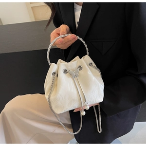 Détail du sac seau blanc avec breloque papillon argentée, cordon perlé et bandoulière chaîne