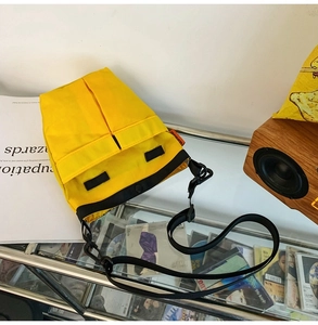 Dettaglio della borsa a tracolla in nylon giallo con cinturini neri e fibbie in stile utility