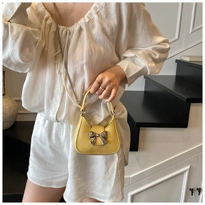 Gros plan du mini sac jaune à nœud papillon avec bandoulière en chaîne métallique fine